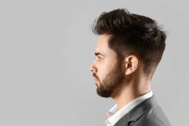 Gri arka planda şık saç stili olan yakışıklı adam.