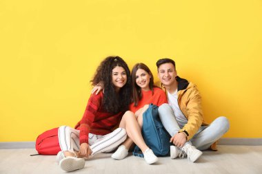 Renk duvarının yanında oturan genç öğrenciler