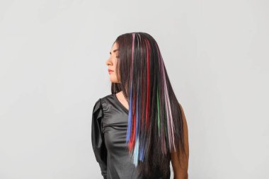 Gri arka planda sıra dışı saçları olan güzel bir genç kadın.