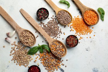 Beyaz arka planda mercimek ve baharatlı kaşıklar