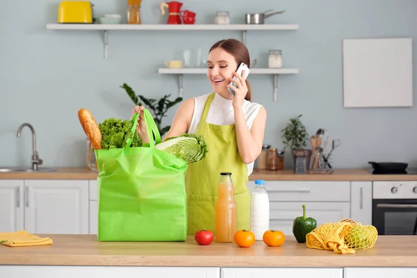 Young woman with food in bag and mobile phone at home