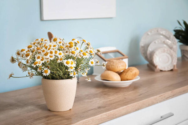 Vase with beautiful chamomiles on table in kitchen