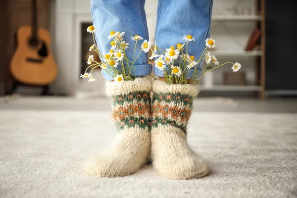 Woman wearing knitted socks with chamomiles at home