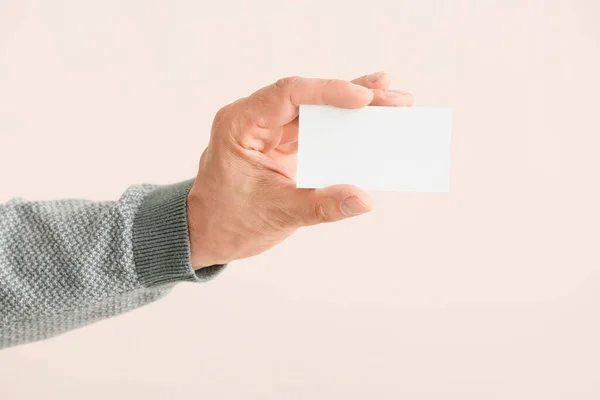 Male hand with blank business card on light background