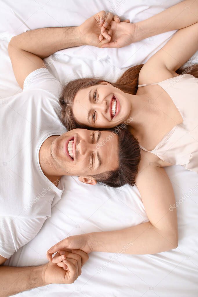 Morning of happy young couple lying in bed