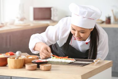 Güzel Asyalı aşçı mutfakta yemek yapıyor.