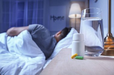 Genç bir adamın yatak odasındaki uyku hapları.