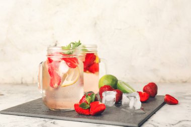 Masada taze çilekli limonata kavanozları var.