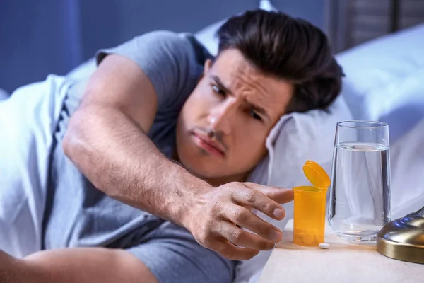 Young man taking sleeping pills at night