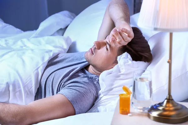 Sleeping pills on table in bedroom of young man
