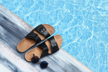 Havuzun kenarında parmak arası terlikler ve güneş gözlüğü.