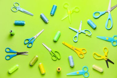 Renk arkaplanında dikiş iplikleri olan makas