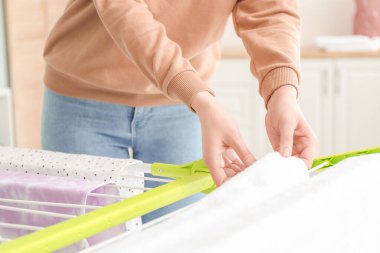 Çamaşırları yıkadıktan sonra çamaşır kurutma makinesine asan genç bir kadın.