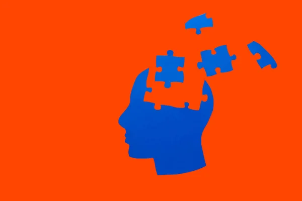 Human head with jigsaw puzzle pieces on color background. Concept of dementia