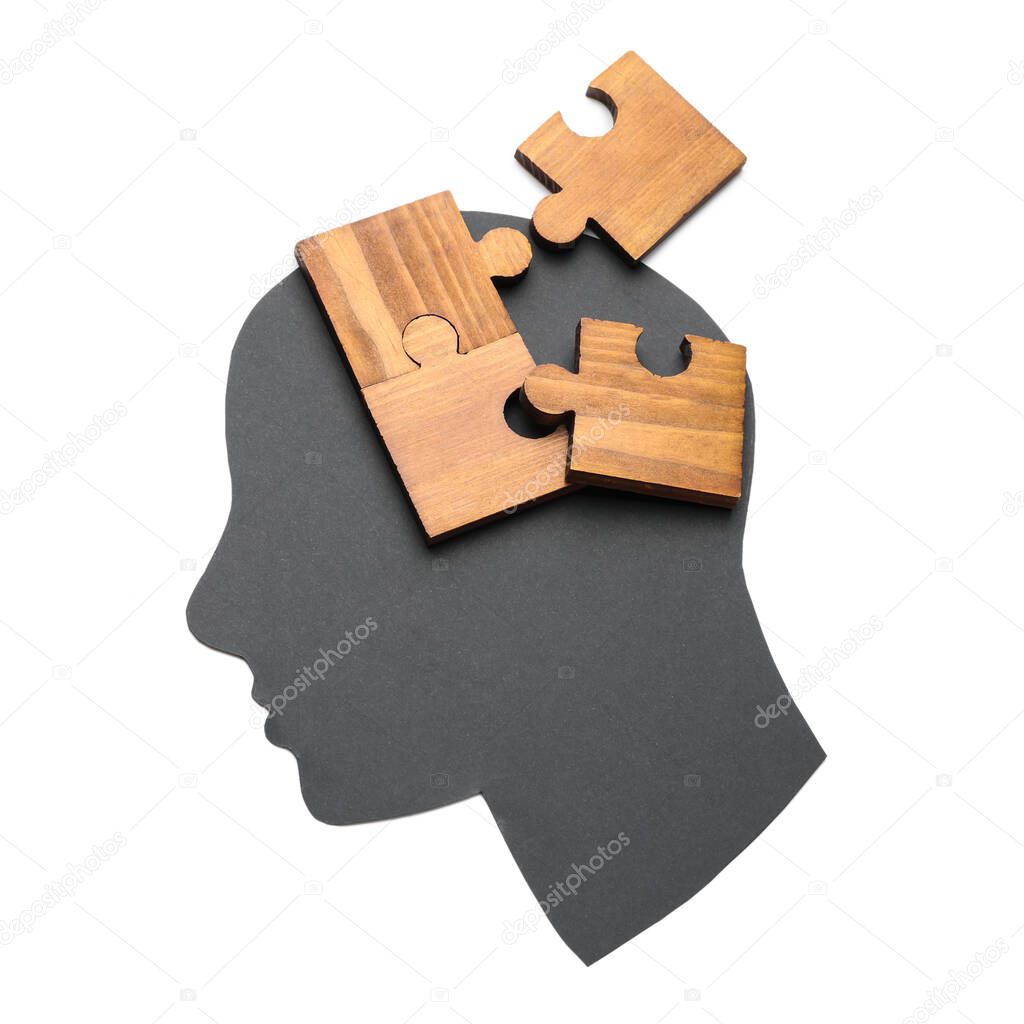 Paper human head and pieces of jigsaw puzzle on white background. Concept of dementia