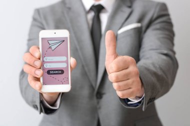 Cep telefonlu bir işadamı arka planda internet üzerinden bilet ayırtıyor.