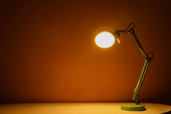 Glowing lamp on table in dark room