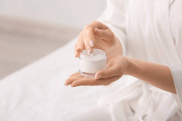 Красивая молодая женщина наносит крем для рук дома
