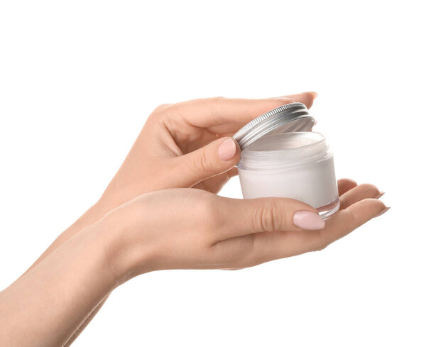 Beautiful young woman applying hand cream against white background