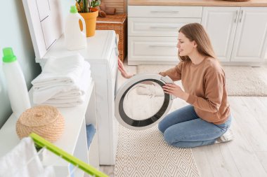 Evde çamaşır yıkayan genç bir kadın.