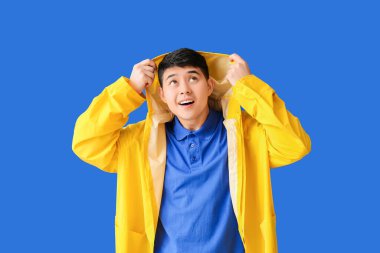 Renkli yağmurluklu genç Asyalı adam