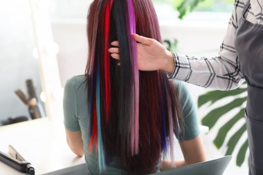 Kuaför, güzellik salonunda genç bir kadınla çalışıyor.