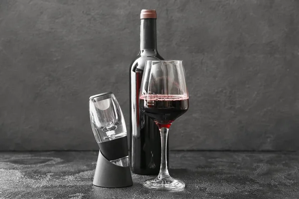 Aerator with bottle and glass of wine on dark background