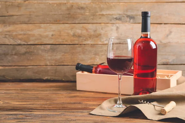 Ahşap zemin üzerinde tirbuşon olan bardak ve şarap şişeleri.