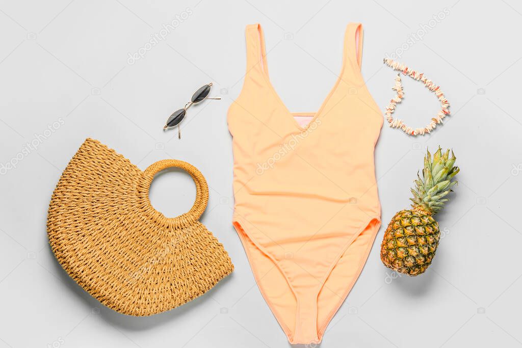 Pineapple with beach accessories on light background