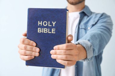 Renkli arka planda İncil 'i olan genç adam, yakın plan