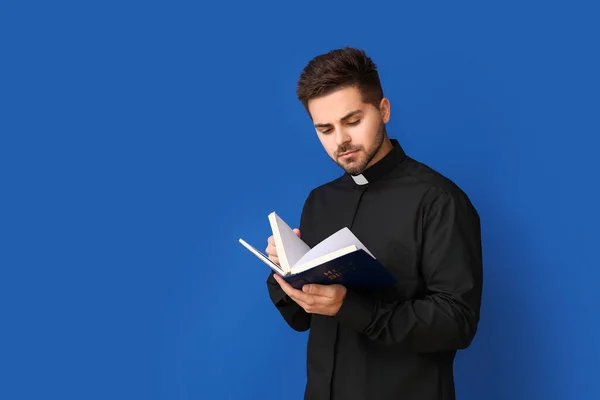 Junger Priester Liest Bibel Auf Farbigem Hintergrund — Stockfoto