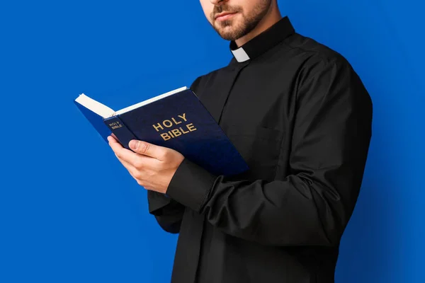 Joven Sacerdote Leyendo Biblia Sobre Fondo Color — Foto de Stock