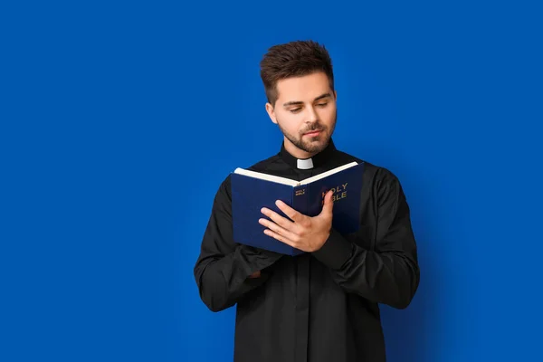 Junger Priester Liest Bibel Auf Farbigem Hintergrund — Stockfoto