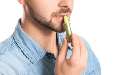 Beyaz arka planda dudak kremi olan yakışıklı genç adam, yakın plan.