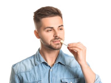 Beyaz arka planda dudak merhemi olan yakışıklı bir genç.