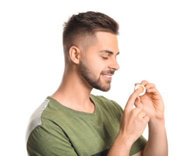 Beyaz arka planda dudak merhemi olan yakışıklı bir genç.