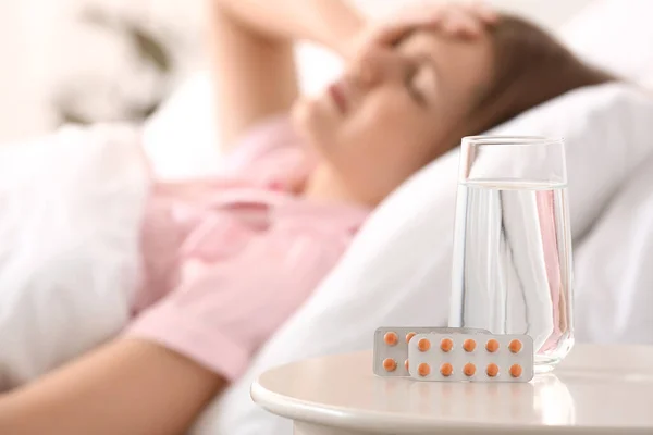 Sleeping pills on table in bedroom of young woman