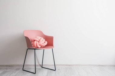 Işık duvarının yanında yastıklı şık bir koltuk