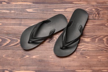 Ahşap arka planda şık parmak arası terlikler