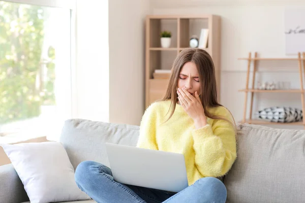 Young woman suffering from sleep deprivation with laptop at home