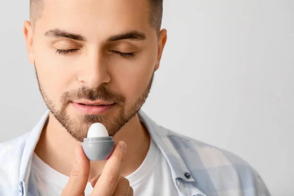 Schöner Junger Mann Mit Lippenbalsam Auf Hellem Hintergrund — Stockfoto