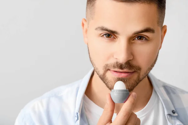 Joven Guapo Con Bálsamo Labial Sobre Fondo Claro — Foto de Stock