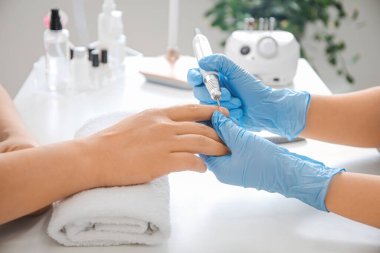 Manikür ustası erkek müşteriyle güzellik salonunda çalışıyor.