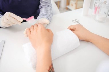 Manikür ustası erkek müşteriyle güzellik salonunda çalışıyor.