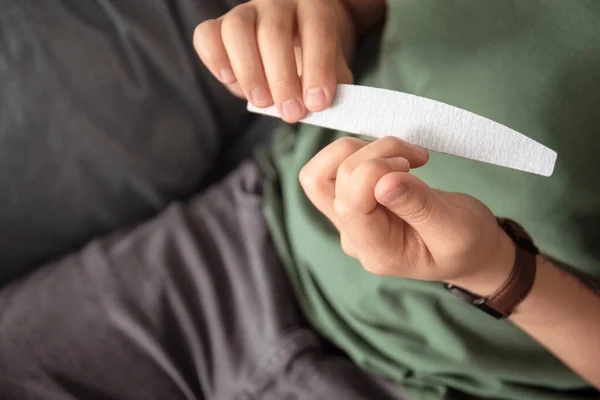 Young Asian man doing manicure at home, closeup