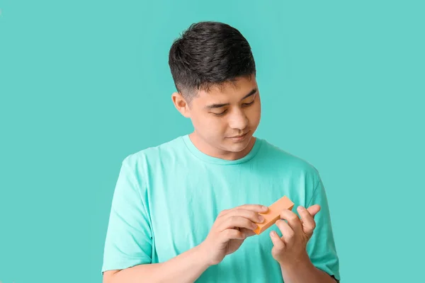 Asian man doing manicure on color background