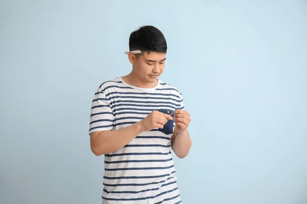 Asian man doing manicure on light background