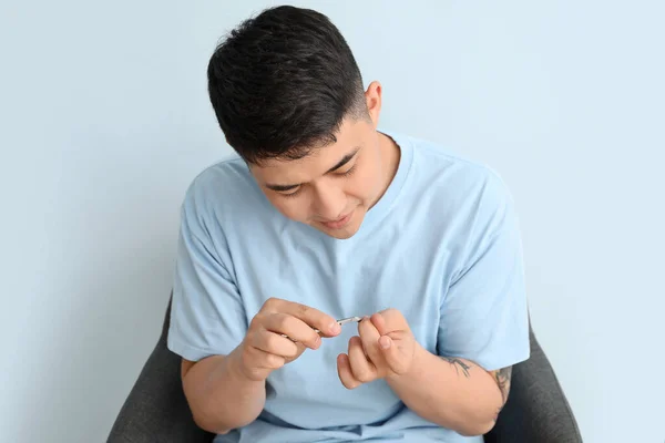 Asian man doing manicure on light background