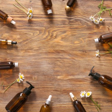 Ahşap arka planda papatya çiçekleri olan kozmetikten yapılmış çerçeve