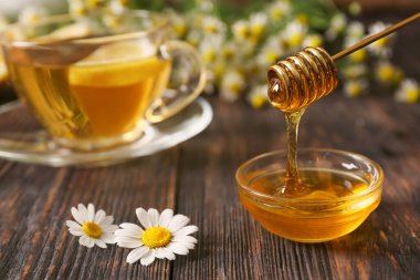 Tahta arka planda papatya çayı ile kase